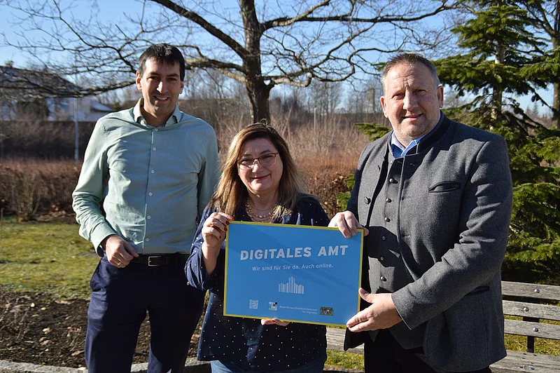 Drei Personen stehen im Herbst nebeneinander. Frau in der mitte zwischen Geschäftsstellenleiter und Bürgermeister.