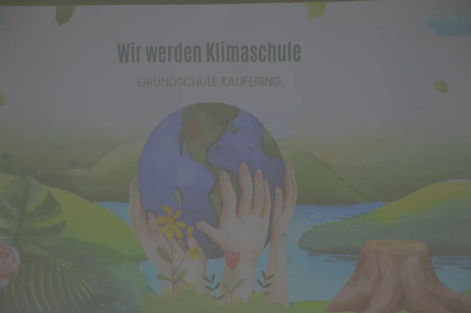Illustration von Händen, die eine Erdkugel halten, umgeben von Pflanzen, mit dem Text 'Wir werden Klimaschule Grundschule Kaufering'