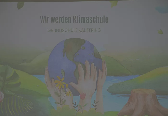 Illustration von Händen, die eine Erdkugel halten, umgeben von Pflanzen, mit dem Text 'Wir werden Klimaschule Grundschule Kaufering'