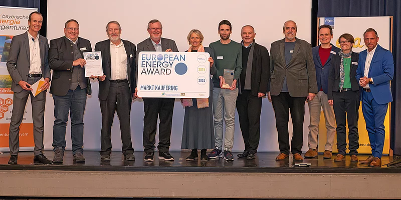 Foto elf Personen stehend mit Auszeichnungsplakat European Energy Award Markt Kaufering