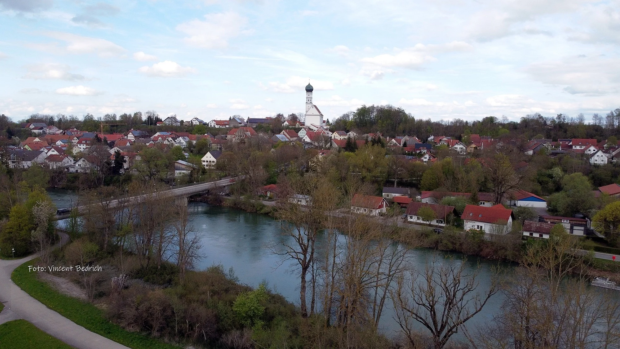 Foto mit Blick auf Kaufering Dorf, mit Lech und Lechbrücke, an einem Herbsttag. Wolkigem Himmel.