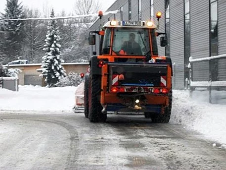 Winter Räumfahrzeug von hinten, räumt die schneebedeckte Straße