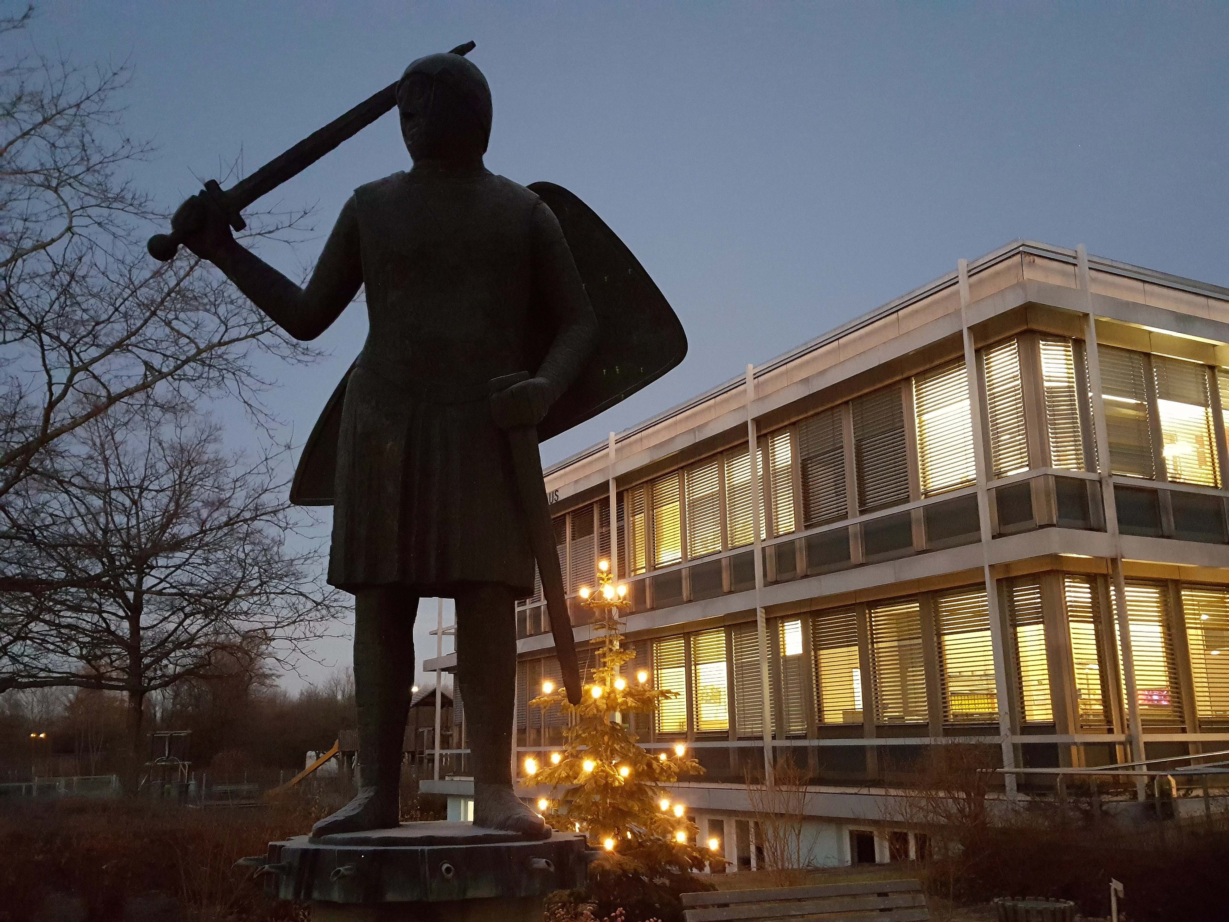 Welfenstatue vor dem im Winter beleuchteten Rathaus